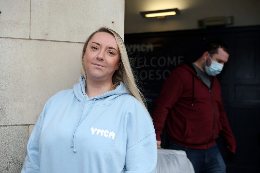 A woman in a YMCA hoodie stands outside a YMCA.