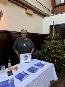 Woman holding booklet next to a Christmas tree.